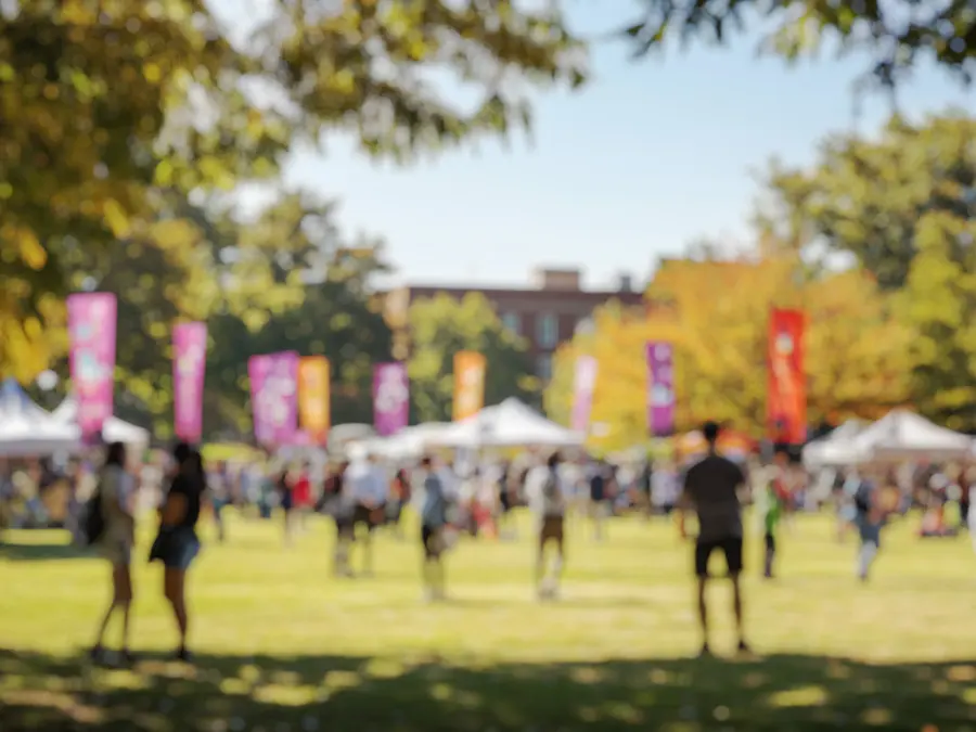 Students gathered on a college campus lawn, out of focus.